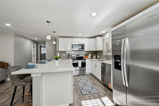 1390 Everett Ct Unit 105, Lakewood, CO 80215 - kitchen with appliances with stainless steel finishes, a sink, a peninsula, light wood-type flooring, and decorative backsplash