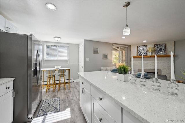1390 Everett Ct Unit 105, Lakewood, CO 80215 - kitchen with stainless steel fridge with ice dispenser, baseboard heating, white cabinets, light wood-style flooring, and pendant lighting
