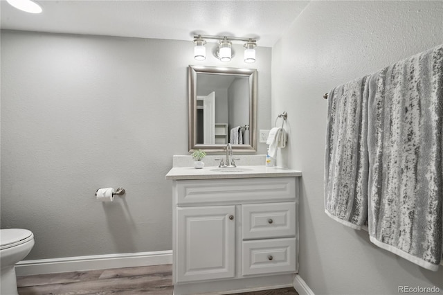 1390 Everett Ct Unit 105, Lakewood, CO 80215 - half bath featuring baseboards, vanity, toilet, and wood finished floors