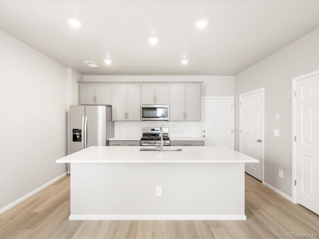 764 N Tempe St, Aurora, CO 80018 - kitchen with backsplash, light countertops, gray cabinets, a kitchen island with sink, and appliances with stainless steel finishes