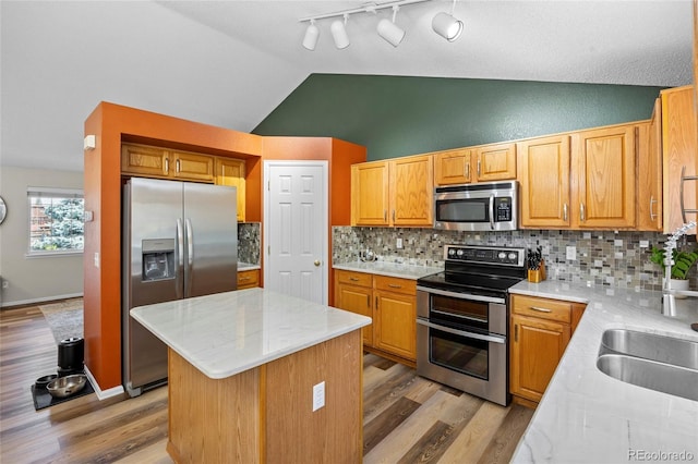 20858 E Progress Ave, Centennial, CO 80015 - kitchen with appliances with stainless steel finishes, vaulted ceiling, a kitchen island, decorative backsplash, and light wood finished floors