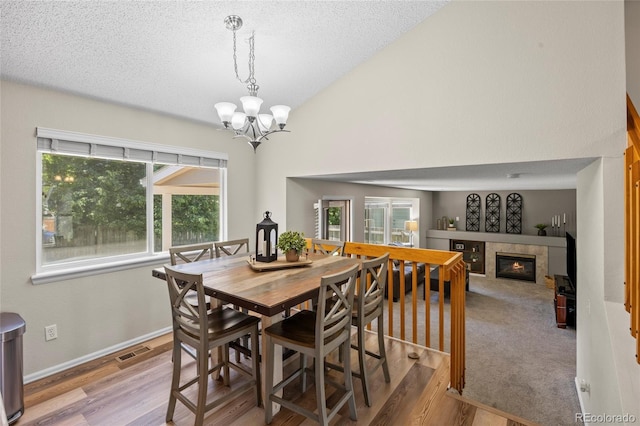 20858 E Progress Ave, Centennial, CO 80015 - dining space featuring plenty of natural light, a chandelier, a tiled fireplace, wood finished floors, and a textured ceiling