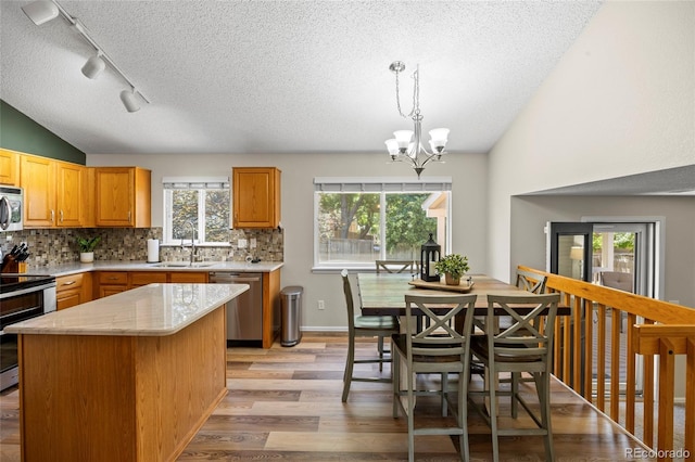 20858 E Progress Ave, Centennial, CO 80015 - kitchen featuring appliances with stainless steel finishes, light wood-style floors, decorative backsplash, a textured ceiling, and a chandelier