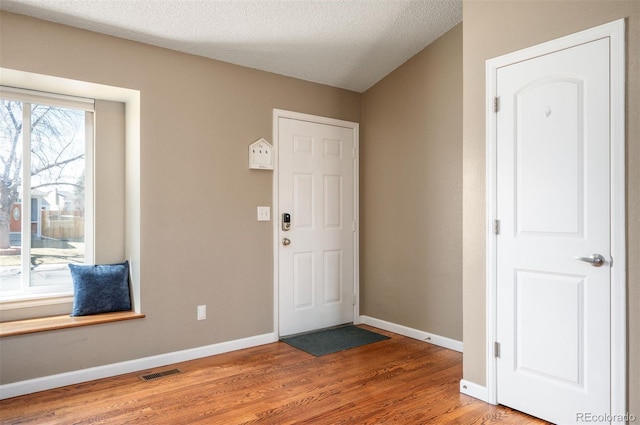 foyer with visible vents, light wood-style flooring, baseboards, and a textured ceiling