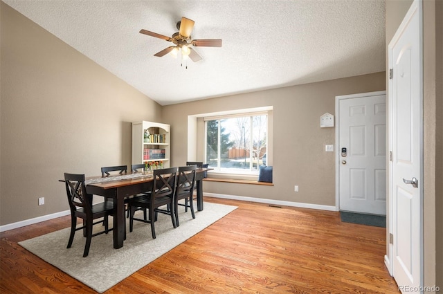 dining room featuring a textured ceiling, baseboards, and wood finished floors