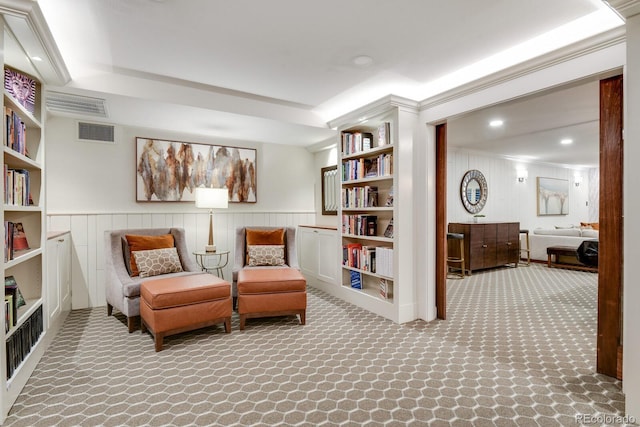 living area with built in shelves and ornamental molding