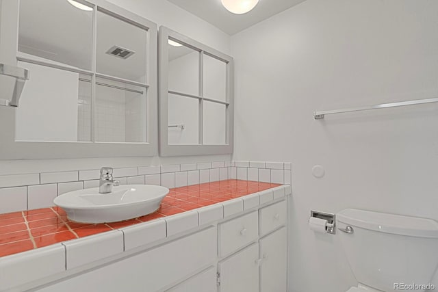 bathroom with decorative backsplash, toilet, and sink