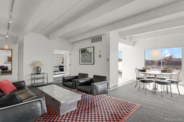 living area with beam ceiling, visible vents, a textured ceiling, and carpet floors