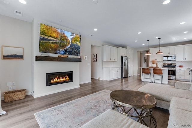 944 Alpine Ridge St, Erie, CO 80516 - living area featuring recessed lighting, baseboards, wood finished floors, and a glass covered fireplace