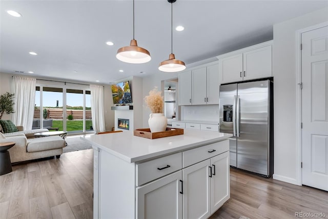 944 Alpine Ridge St, Erie, CO 80516 - kitchen with stainless steel fridge with ice dispenser, open floor plan, light wood-type flooring, light countertops, and white cabinets