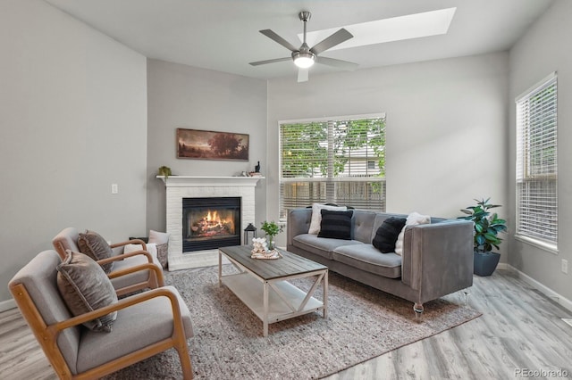 6868 Los Reyes Cir, Colorado Springs, CO 80918 - living area with light wood-style floors, a ceiling fan, a skylight, a glass covered fireplace, and baseboards