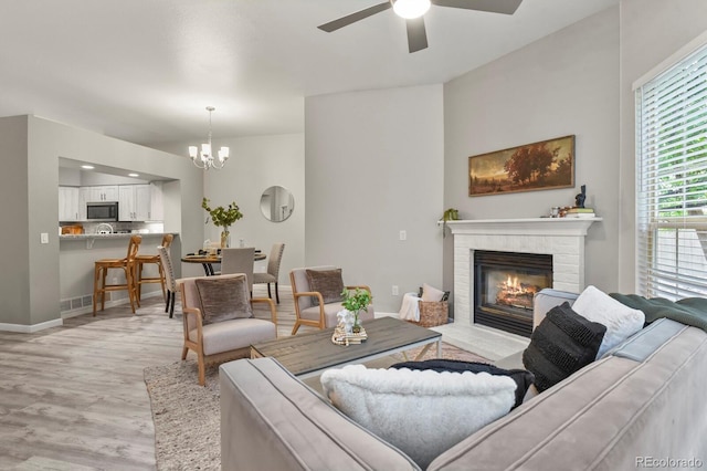 6868 Los Reyes Cir, Colorado Springs, CO 80918 - living area featuring a ceiling fan, a chandelier, light wood-type flooring, a glass covered fireplace, and baseboards