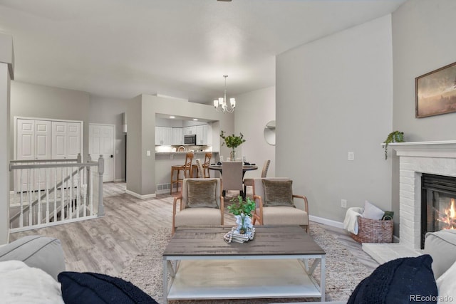 6868 Los Reyes Cir, Colorado Springs, CO 80918 - living room featuring a chandelier, light wood-style floors, baseboards, and a brick fireplace