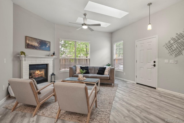 6868 Los Reyes Cir, Colorado Springs, CO 80918 - living area with light wood-style floors, baseboards, a brick fireplace, a skylight, and ceiling fan