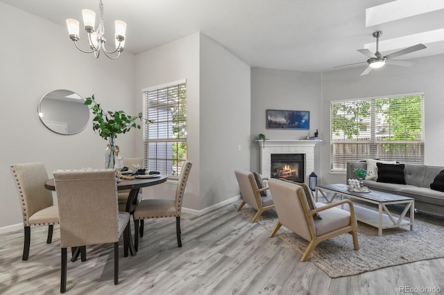 6868 Los Reyes Cir, Colorado Springs, CO 80918 - dining room with light wood-type flooring, a brick fireplace, baseboards, a chandelier, and a ceiling fan