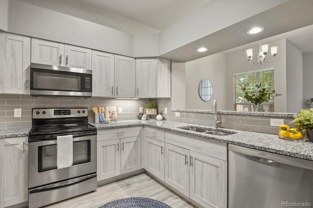 6868 Los Reyes Cir, Colorado Springs, CO 80918 - kitchen with appliances with stainless steel finishes, a sink, light wood-style flooring, decorative backsplash, and light stone countertops