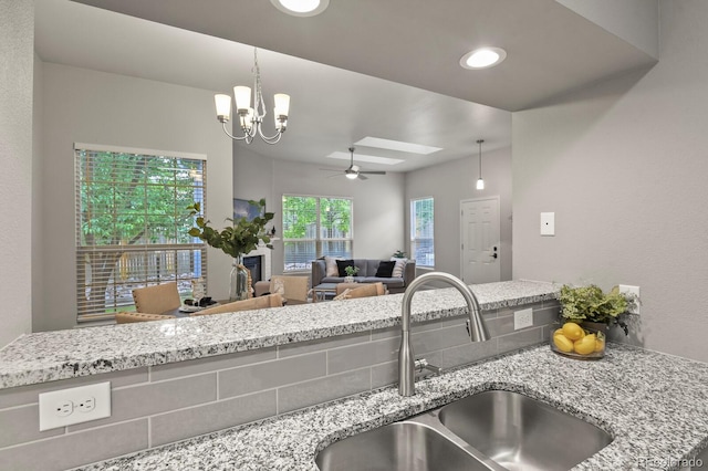 6868 Los Reyes Cir, Colorado Springs, CO 80918 - kitchen with a sink, ceiling fan, a chandelier, and light stone countertops