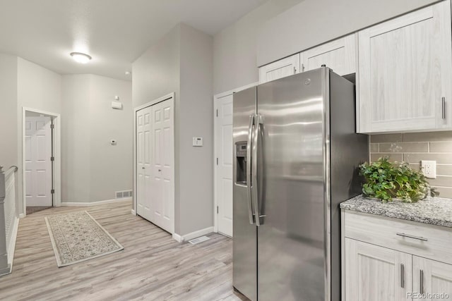 6868 Los Reyes Cir, Colorado Springs, CO 80918 - kitchen featuring stainless steel fridge, light wood-style flooring, decorative backsplash, baseboards, and light stone countertops
