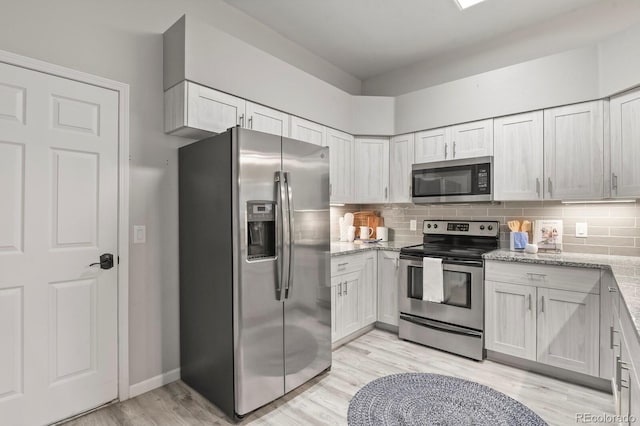 6868 Los Reyes Cir, Colorado Springs, CO 80918 - kitchen featuring appliances with stainless steel finishes, light stone countertops, light wood-type flooring, tasteful backsplash, and baseboards