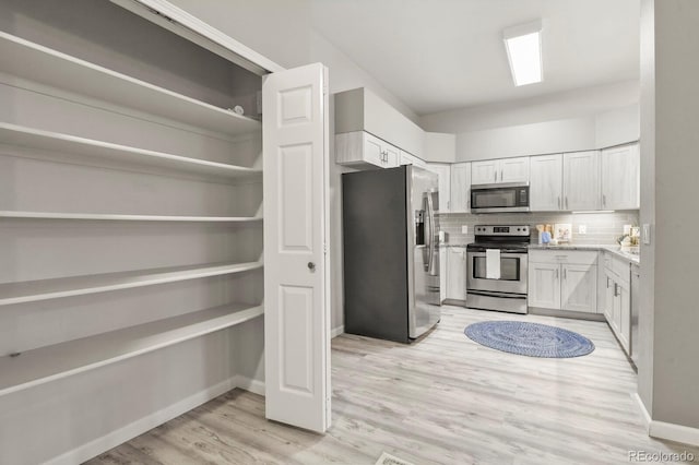 6868 Los Reyes Cir, Colorado Springs, CO 80918 - kitchen with appliances with stainless steel finishes, decorative backsplash, light wood-style floors, baseboards, and white cabinets