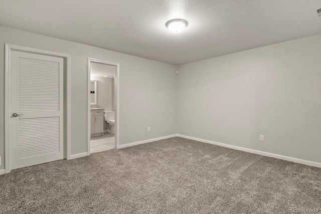 6868 Los Reyes Cir, Colorado Springs, CO 80918 - unfurnished bedroom featuring light carpet, baseboards, ensuite bath, and a textured ceiling