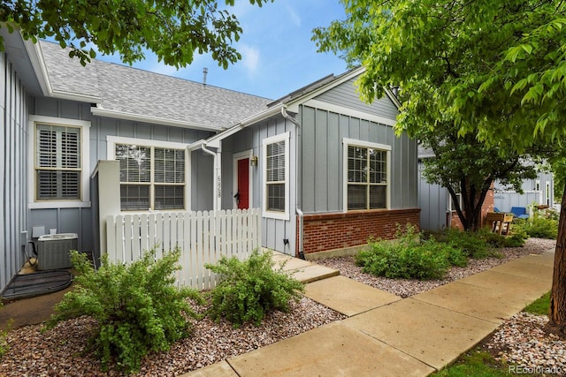 6868 Los Reyes Cir, Colorado Springs, CO 80918 - view of front of home featuring board and batten siding, central AC unit, and a shingled roof
