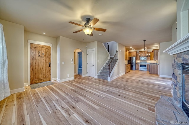 304 Cottonwood Cir Unit A, Salida, CO 81201 - unfurnished living room with a stone fireplace, stairs, light wood-type flooring, ceiling fan, and arched walkways