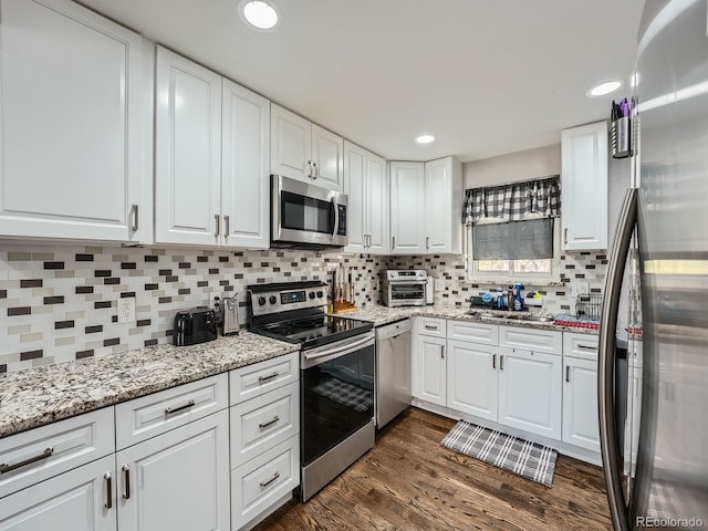 kitchen with white cabinetry, stainless steel appliances, and dark hardwood / wood-style floors