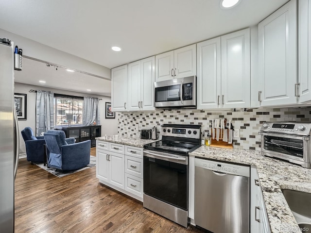 kitchen with white cabinets, stainless steel appliances, dark wood-type flooring, and light stone countertops