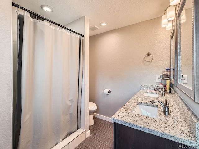 bathroom featuring vanity, a textured ceiling, a shower with shower curtain, hardwood / wood-style flooring, and toilet