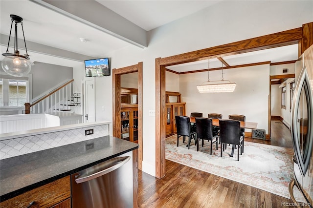 kitchen with appliances with stainless steel finishes, backsplash, pendant lighting, and dark wood-type flooring