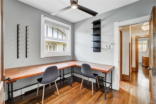 office space with built in desk, ceiling fan, hardwood / wood-style flooring, and a baseboard heating unit