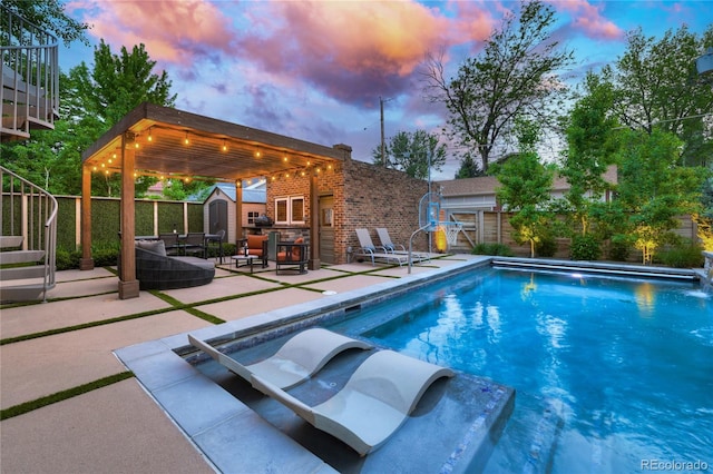 pool at dusk featuring a patio area and a storage unit