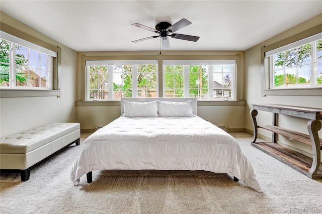 bedroom with carpet flooring, ceiling fan, a baseboard radiator, and multiple windows