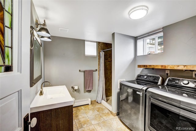 washroom with light tile flooring, sink, a baseboard radiator, and washer and dryer