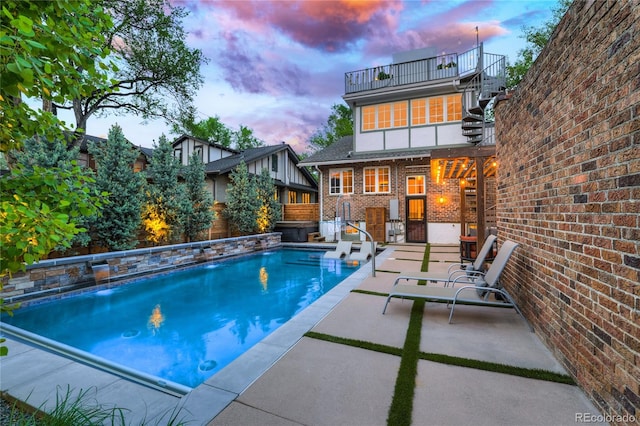 pool at dusk featuring a patio area and pool water feature