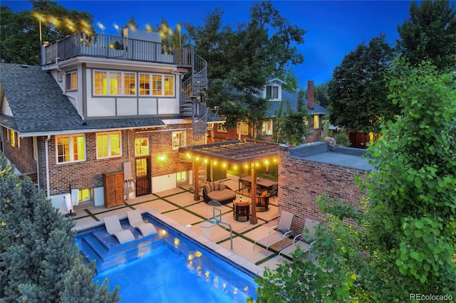 back house at twilight with a patio area and a balcony