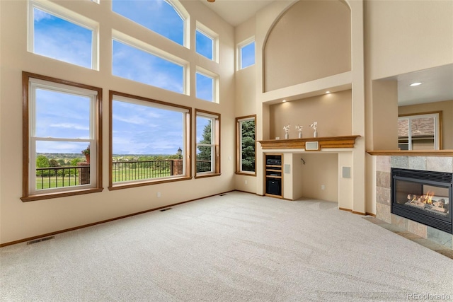 6323 S Sicily Way, Aurora, CO 80016 - unfurnished living room featuring carpet flooring, a tile fireplace, baseboards, and a high ceiling