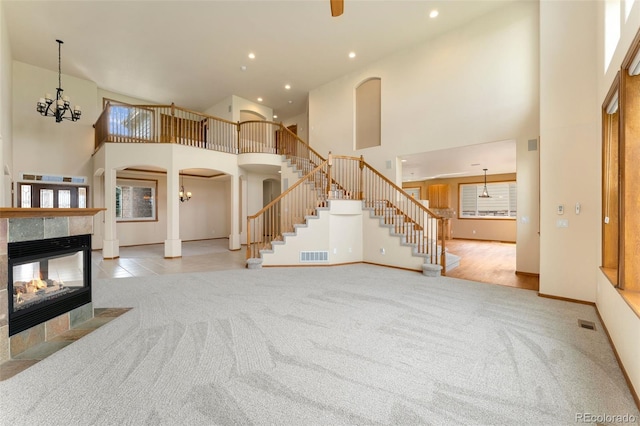 6323 S Sicily Way, Aurora, CO 80016 - unfurnished living room featuring carpet, a towering ceiling, stairway, a fireplace, and arched walkways