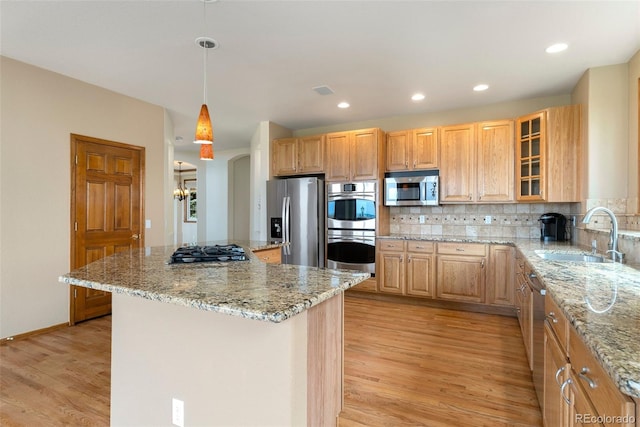 6323 S Sicily Way, Aurora, CO 80016 - kitchen featuring appliances with stainless steel finishes, a sink, light wood finished floors, light stone counters, and a kitchen island