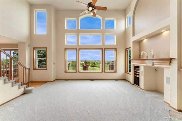 6323 S Sicily Way, Aurora, CO 80016 - unfurnished living room featuring carpet floors, a high ceiling, ceiling fan, stairway, and baseboards