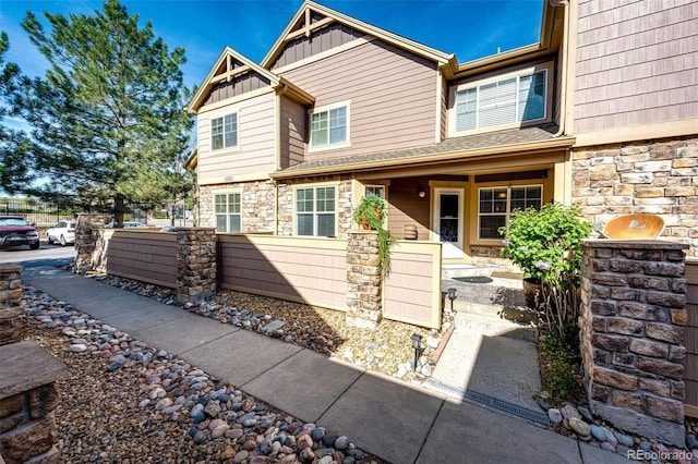 townhome / multi-family property featuring fence, board and batten siding, and stone siding
