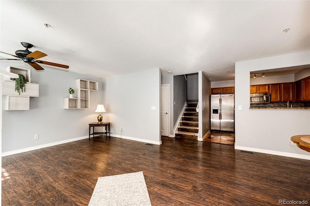 unfurnished living room with a ceiling fan, baseboards, wood finished floors, and stairway
