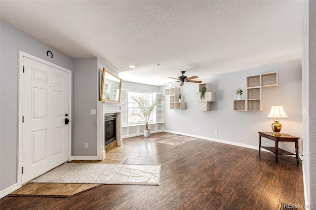 unfurnished living room featuring baseboards, a fireplace with flush hearth, a ceiling fan, and wood finished floors