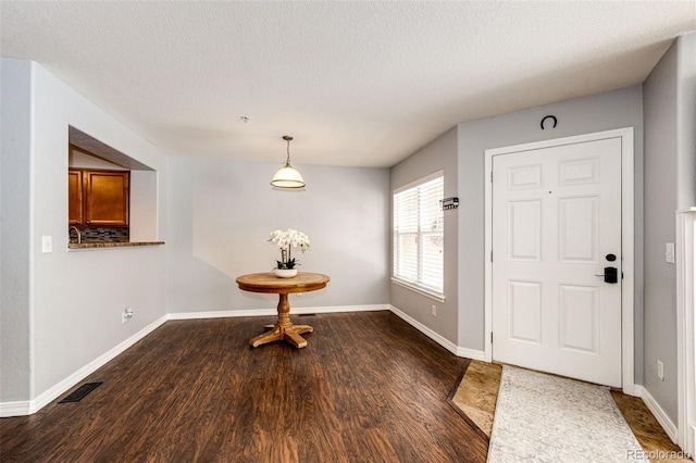 entryway featuring a textured ceiling, baseboards, visible vents, and wood finished floors