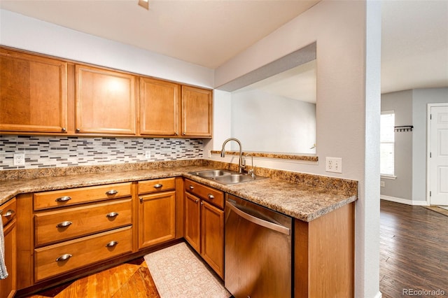 kitchen featuring stainless steel dishwasher, brown cabinetry, a sink, and dark wood-type flooring