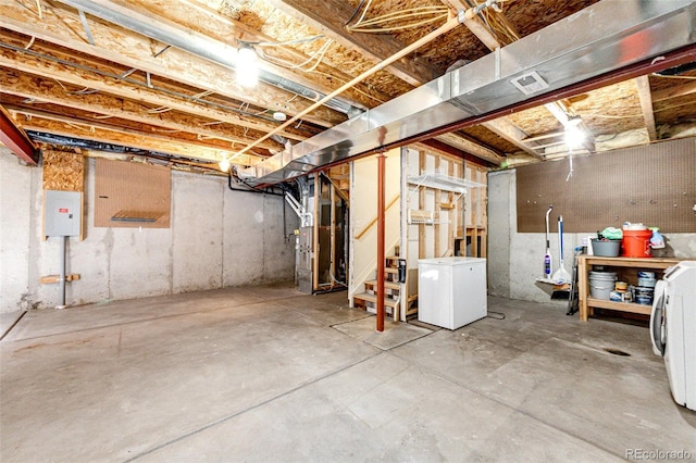 unfinished below grade area featuring heating unit, washer / dryer, refrigerator, stairway, and electric panel