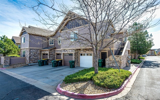 view of front of property with an attached garage, driveway, and stone siding