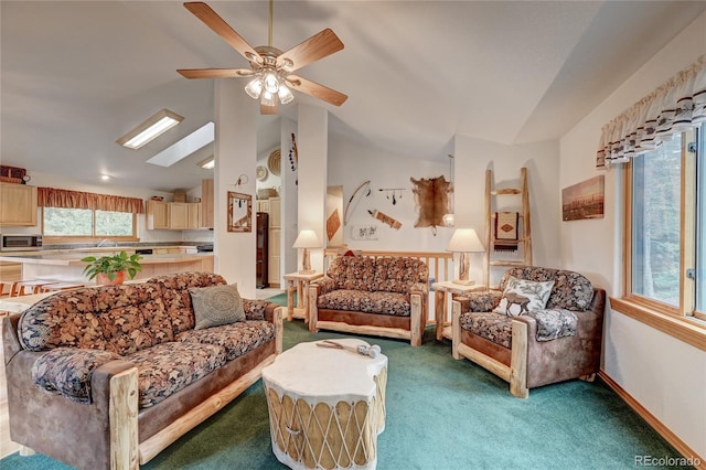 carpeted living room featuring lofted ceiling with skylight and ceiling fan