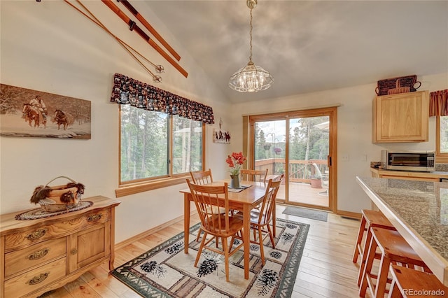 dining space featuring a chandelier, light hardwood / wood-style floors, and vaulted ceiling